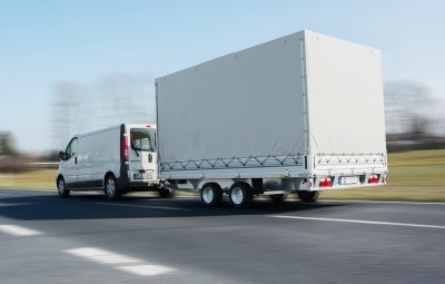 White Delivery Van Pulling a Large White Box Trailer on a Highway Daytime with Clear Blue Sky