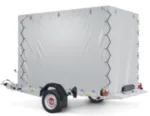 White enclosed cargo trailer on a small hitch-mounted trailer, visible rear ramp and wheel, ready for transport