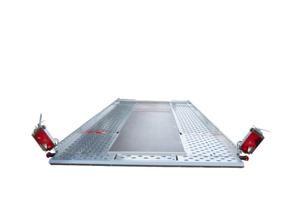 Metal perforated loading ramp with red safety lights on each end, viewed from ground level (trailer/transport use)