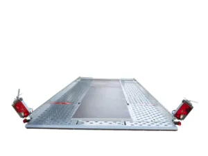 Metal perforated loading ramp with red safety lights on each end, viewed from ground level (trailer/transport use)