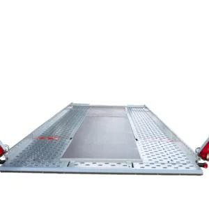 Metal perforated loading ramp with red safety lights on each end, viewed from ground level (trailer/transport use)