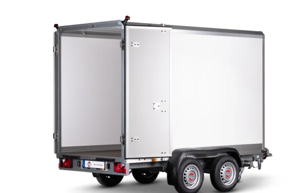 Silver cargo trailer with rear doors open, showing a large white interior, mounted on a dual-axle chassis with red taillights and a small license plate area at the back.
