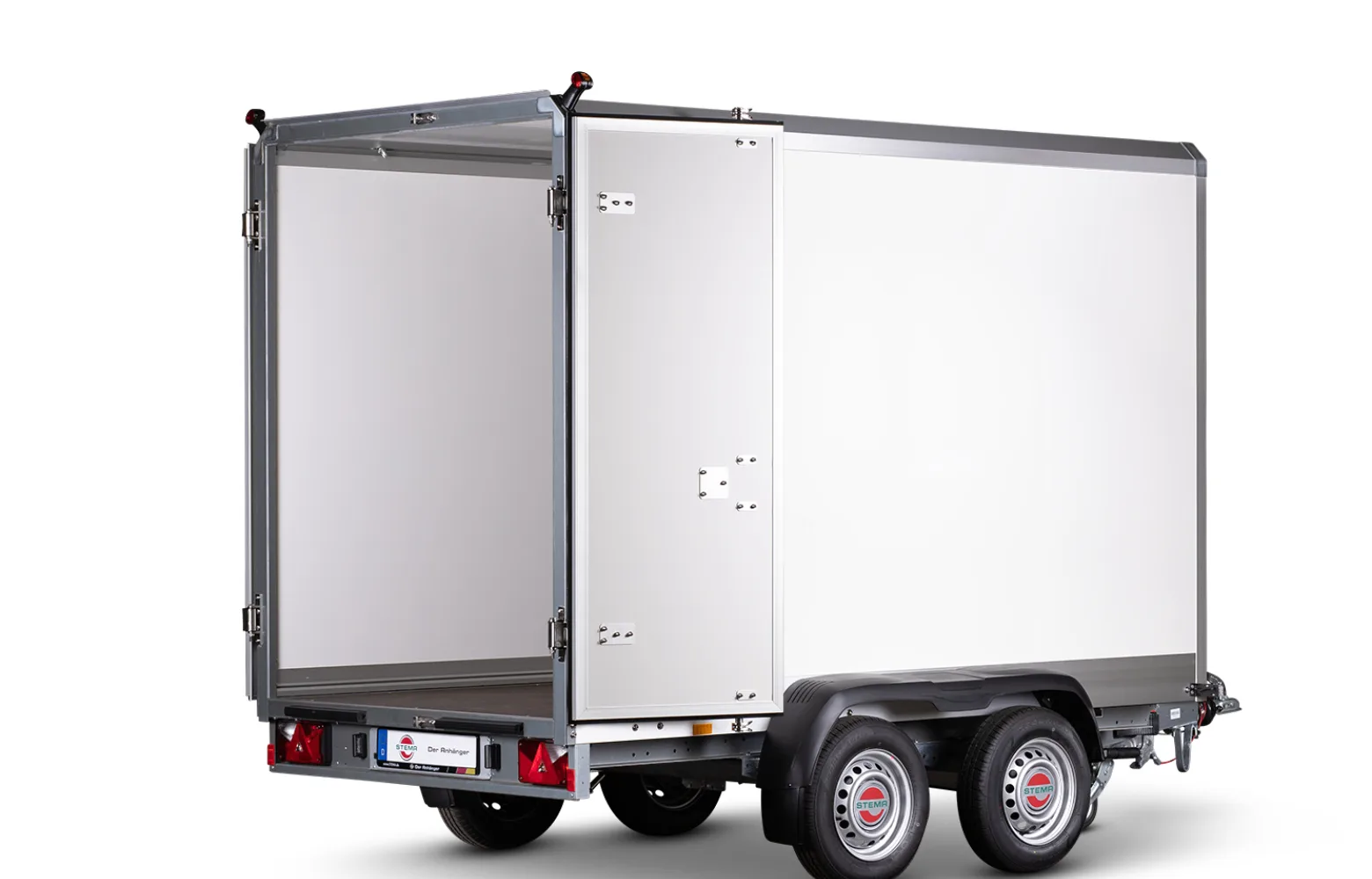 Silver cargo trailer with rear doors open, showing a large white interior, mounted on a dual-axle chassis with red taillights and a small license plate area at the back.