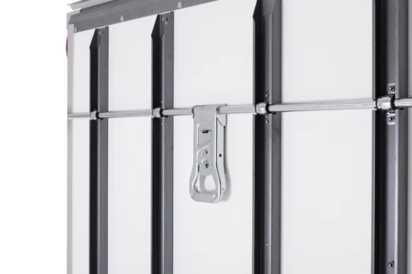 Close-up of a metal latch and horizontal locking bar securing a white industrial door.